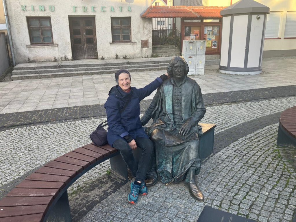 Kerstin auf einer Bank in Frombork neben einer Kopernikus-Statue